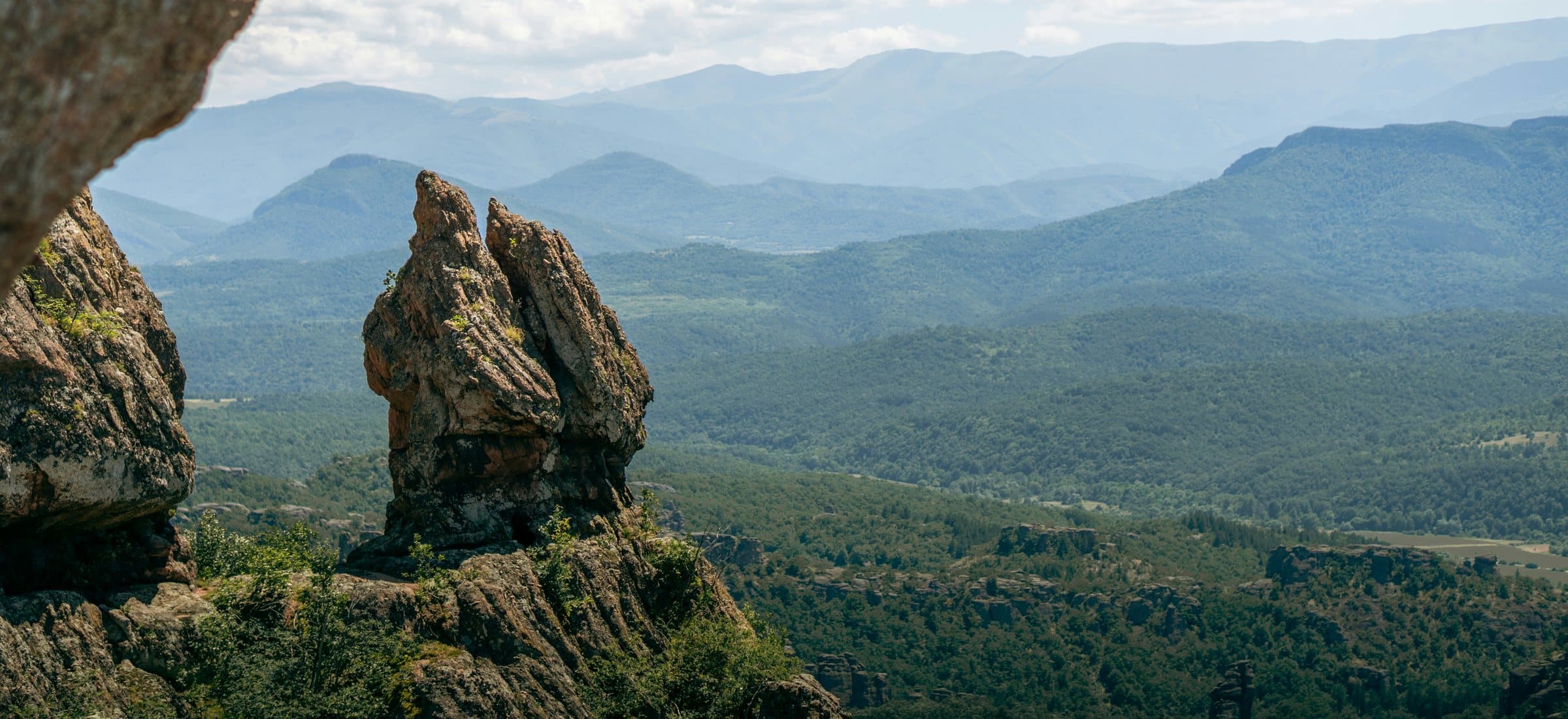 Sandstone pillars of the Belogradchik Rocks against layered, forested mountain ridges, Bulgaria