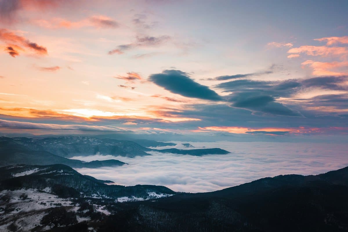 Sunset over a sea of cloud below dark, snow-dusted ridges near Vratsa, Bulgaria